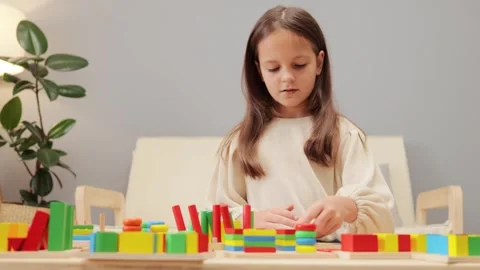 Developing Montessori activities. Focused concentrated brown haired schoolgirl Stockbeeldmateriaal 256290392