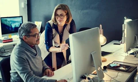 Developing their ideas together. two businesspeople working late in an office. Stock Photos
