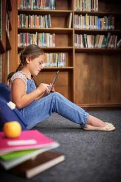 Developing through the digital age. a young girl using a digital tablet at Stock Photos