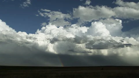 Developing thunderheads blowing over prairie with rainbow on horizon Video stock 59525450