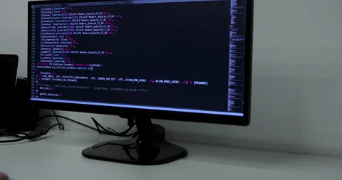 Develper writing sql code in monitor working from home Stock Footage 228578604