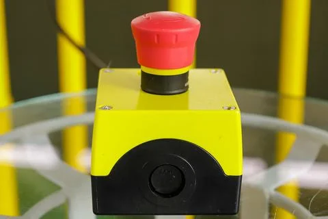 Device for activating a system. In the photo a yellow box with a red button o Stock Photos