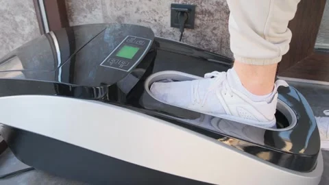 A device for automatically putting on shoe covers, a man in sneakers puts on Stock Footage 241004455