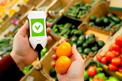 Device in hand measuring nitrates and pesticides on market vegetables and fruits Stock Photos