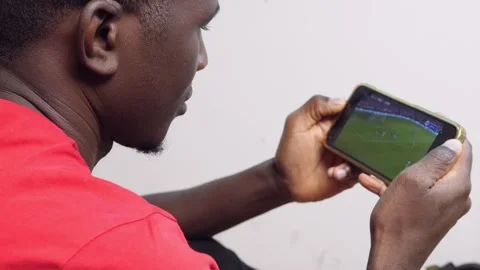 Device, streaming - black man fan concentrated watching soccer match on phone Stock Footage 240322043