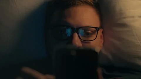 Device. A young guy under a blanket is concentrated and addicted to social n Stock Footage 252389923
