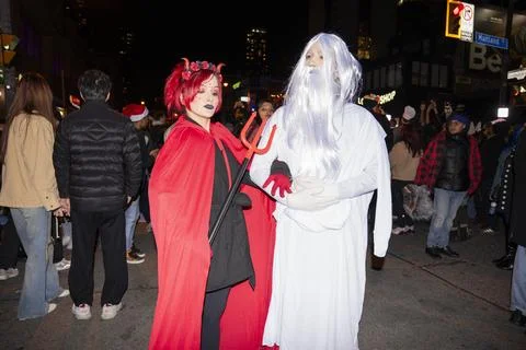 Devil and ghost costumes posing during Halloween street celebration at night Stock Photos