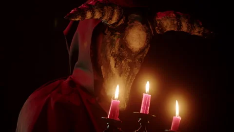 Devil with cow skull head holding burning candles. Demon with horns conjuring Stock Footage 161071220