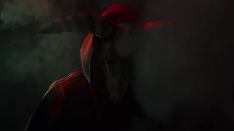 Devil with cow skull head making rite in smoke. Demon with horns conjuring close Stock Footage