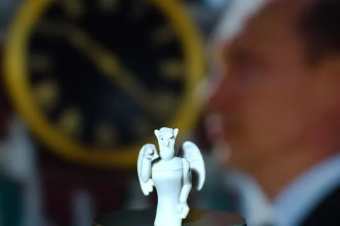 Devil figurine on blurred background of clock face Stock Photos