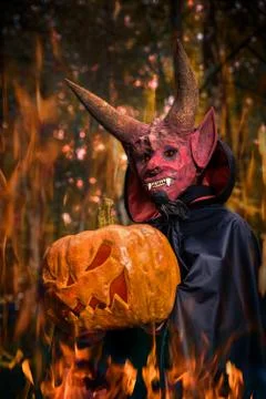 Devil on fire with a pumpkin in his hands for Halloween Stock Photos