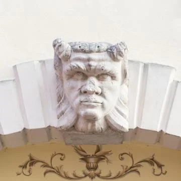 Devil head carved above the stone arch of an Italian villa. Stock Photos