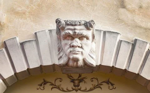 Devil head carved above the stone arch of an Italian villa. 스톡 사진