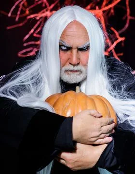Devil man with pumpkin in hand. Bearded man in witch costume ready to Hallowe Stock Photos