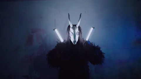 The devil monster dances with RGB sticks in his hands. A man in a scary mask Stock Footage 266920077