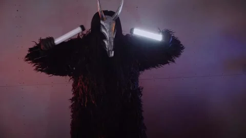 The devil monster dances with RGB sticks in his hands. man in a scary mask Stock Footage 266928289