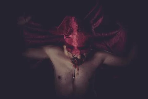 Devil, naked man on large red cloth over his eyes Foto stock