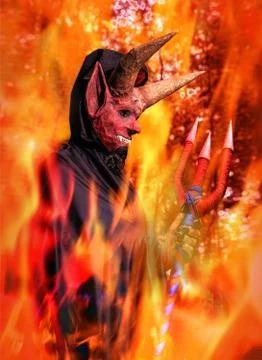 Devil in a raincoat on a background of fire with a trident in his hands Foto stock