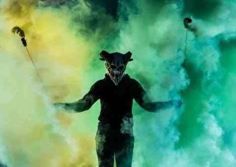 Devil with scary mask surrounded by coloured smoke Foto stock