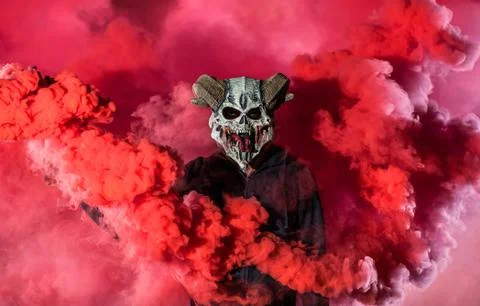 Devil with scary mask surrounded by red smoke Stock Photos