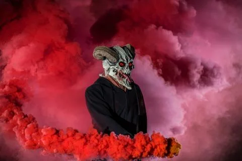 Devil with scary mask surrounded by red smoke Stock Photos