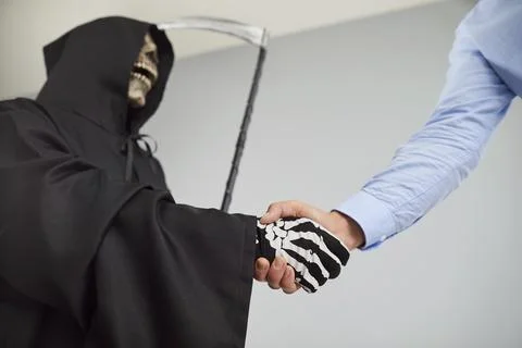 Devil shaking hands with a man employee making an agreement on gray background. Foto stock