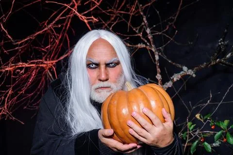 Devil vampire man with Halloween pumpkin. Magician witcher old man with pumpk Stock Photos