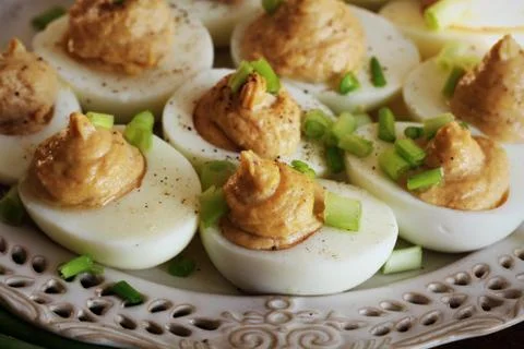 Deviled eggs with cod livers with leek on white plate. Rustic wooden table Stock Photos