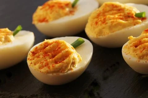 Deviled eggs with red pepper on black background Stock Photos