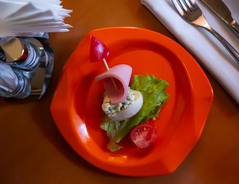 Devilled egg in shape of ship with sausage slice and fresh vegetables Stock Photos