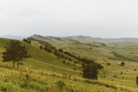Devil's Finger mountain landscape with rolling green hills and cloudy sky, Altai Stock Photos
