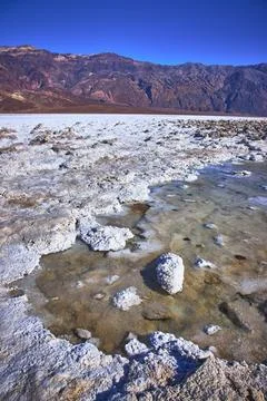 Devil's Golf Course Salt Formations and Rugged Mountains Under Clear Blue Sky Stock Photos