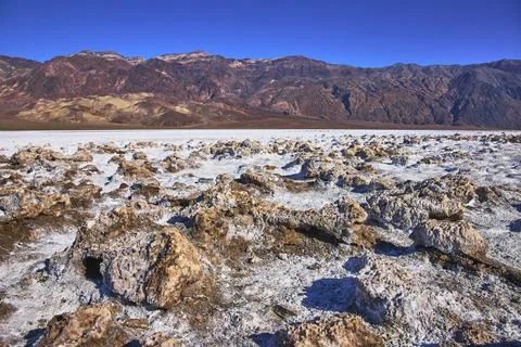 Devil's Golf Course Salt Formations and Desert Mountains Under Clear Blue Sky Stock Photos