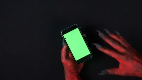 Devil's hand uses smartphone with a green screen. Video stock 80426065