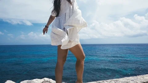 Девочка стоит над обрывом в белом платье и смотрит на лазурное море Stock-Footage 96005788