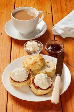 Devon cream tea, scones, jam, cream and a cup of tea, on an old pine table. Stock Photos