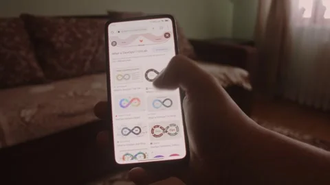 DevOps. Searching information about DevOps on mobile phone screen. Stock Footage 249819264