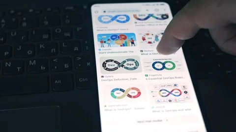 DevOps. Searching information about DevOps on mobile phone screen. Stock Footage 249820114