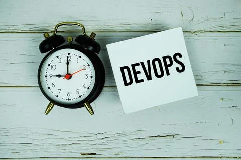 Devops text message on paper with alarm clock on wooden background Stock Photos