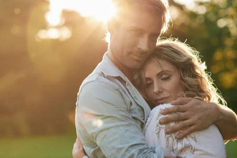 Devoted young couple hugging under the setting sun Stock Photos