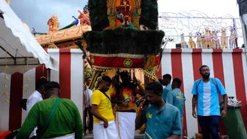 A devotee carries an elaborate kavadi adorned with peacock feathers and deity Stock Footage 303500348