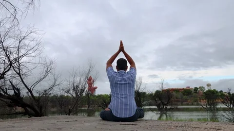 Devotee meditating with Statue of holy Lord Shiva with dramatic sky near Stock Footage 289856834