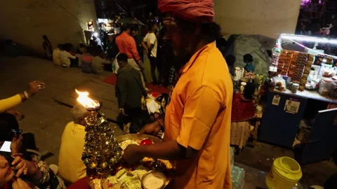 Devotee offering holy oil lamp aarti to visitors at night Stock Footage 272309429