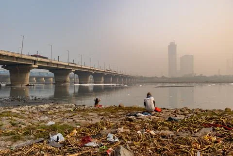 Devotee performing holy rituals at Polluted River shore with Toxic Foam and.. Фото