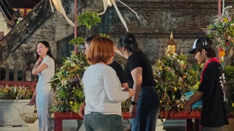 Devotee placing flowers on flower-covered Buddha head at Wat Chedi Luang 스톡 동영상 336961738