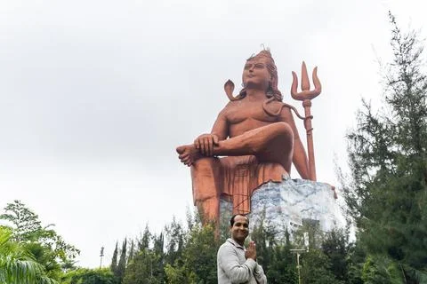 Devotee praying to the hindu god lord shiva huge isolated statue at morning Stock-Fotos