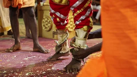 A devotee tying ornaments to dance performer's legs Stock Footage 208375393