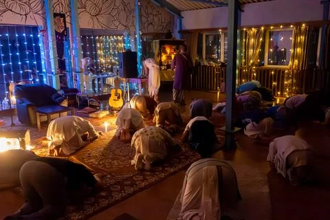 Devotees in full prostration before illuminated altar during evening kirtan Foto stock