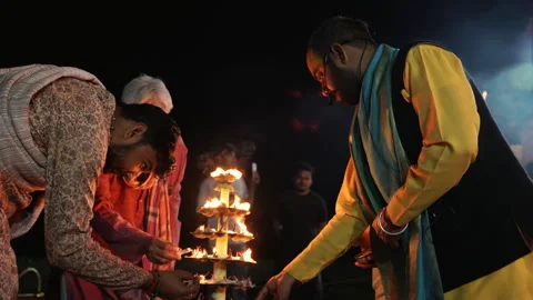 Devotees lighting multi tiered brass oil lamp stand during evening Aarti Stock Footage 341325404