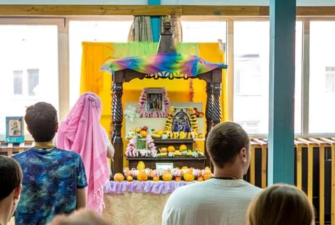 Devotees standing before deity altar in ISKCON temple hall Stock Photos